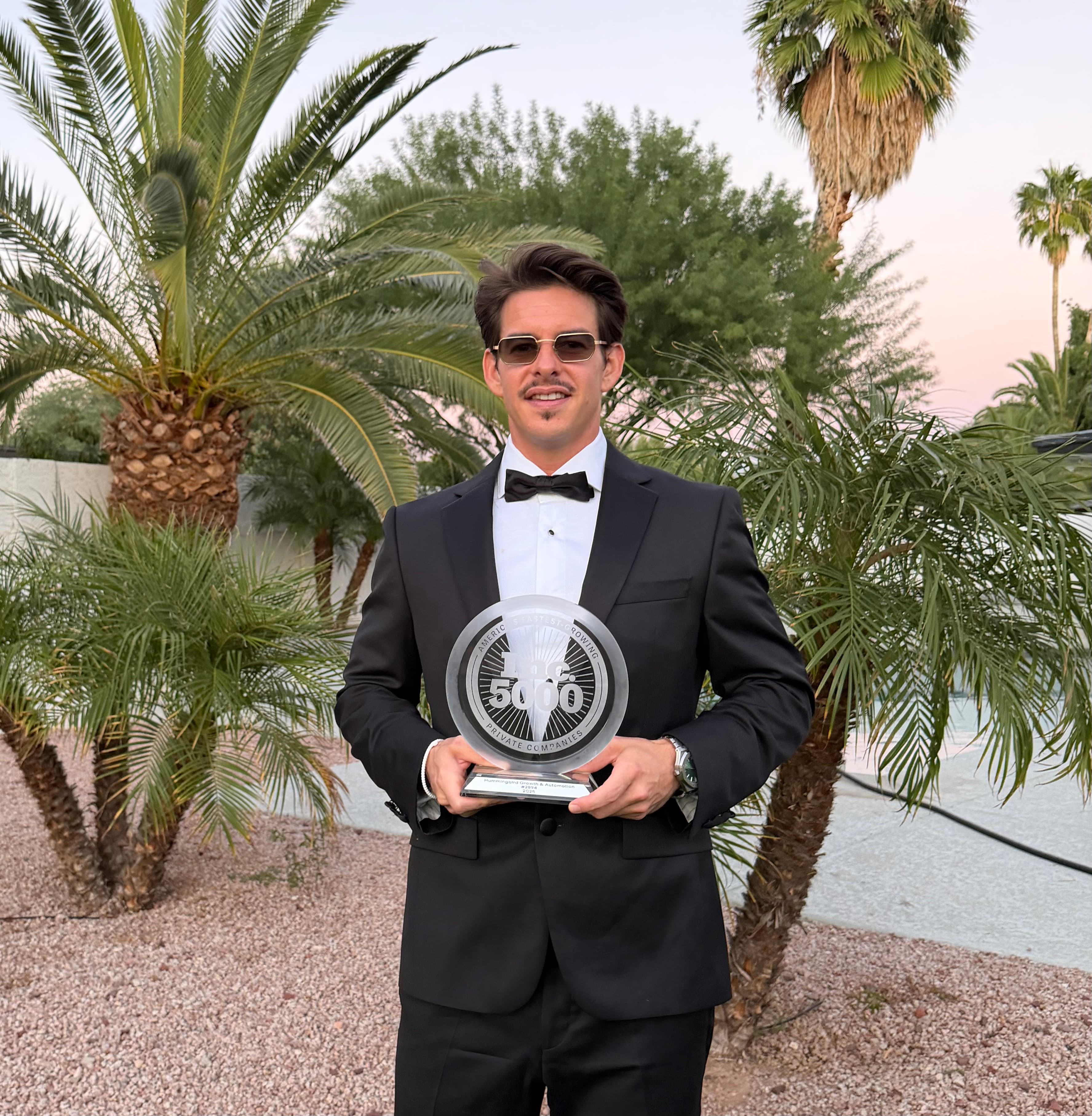 Matt, founder of CHAARM AI & Automation, holding the Inc 5000 trophy